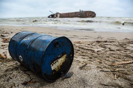 Shipwrecked tanker with an oil barrel in the foreground.
