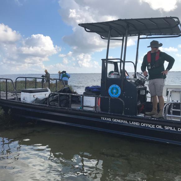 TX GLO Oil Spill boat by shore with people cleaning the coast.